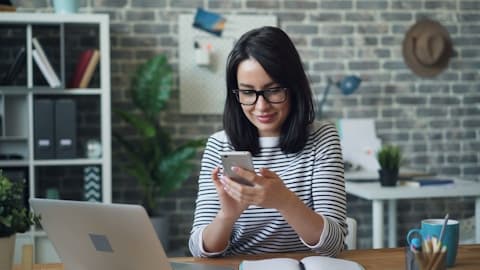 Woman checking her phone at her desk