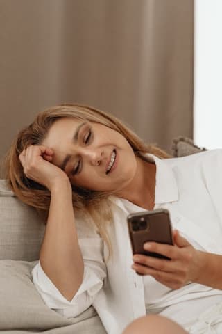 Woman relaxing on a couch smiling at her phone